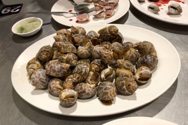 Yerel bir restoranda servis edilen ızgara benekli deniz salyangozu.