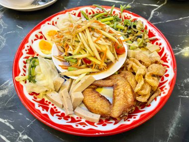 Tayland usulü som tam tabağı ızgara tavuk, domuz sosisi, haşlanmış yumurta ve domuz çıtırtısı.