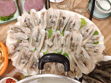 Fresh Asian razor clams arranged on a plate, prepared raw for Chinese-style hotpot.