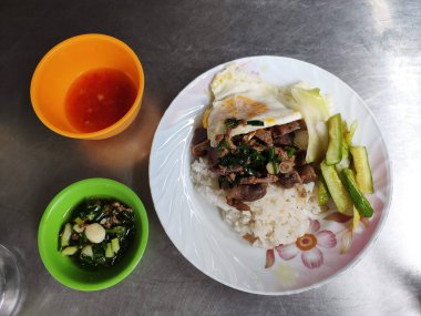 Steamed rice topped with stir fried chicken innards and a fried egg, served with dipping sauce.