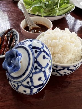 Buharda pilavla dolu mavi ve beyaz seramik kâse ve Tayland restoranının masasının kapağı..