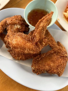 Tayland restoranında tatlı ve baharatlı sosla servis edilen kızarmış tavuk kanatları..