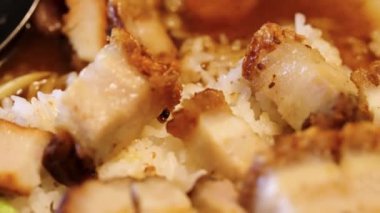 Buharda pişmiş pirincin üstünde yeşil soğan ve susam tohumlarıyla süslenmiş bir Çin yemeği. Çıtır domuz eti sulu ve lezzetlidir, mükemmel bir tat ve tatlı dengesi vardır..