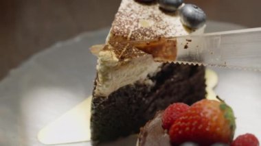 Lezzetli bir Kara Orman pastasının katmanlarından süzülen bir bıçak. Zengin çikolata, pofuduk krema ve turta kirazları her kesikte sergileniyor, umut verici. Yüksek kalite 4k görüntü