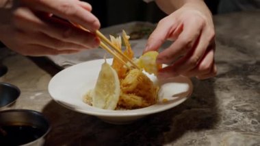 Japon tempura kasesinin sanatsal yaratılışına tanık olun. Usta şef titizlikle çıtır çıtır tempura parçalarını buharda pişmiş pirinçten bir yatağa yerleştiriyor. Canlı renkler ve titiz sunum .