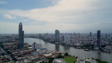 Nehir kenarında bulutların zarif bir şekilde dans ettiği bir şehrin büyüleyici güzelliğini tecrübe edin. Şehrin ışıkları ruhani hareketlerle parıldarken zamanın akışı ustalıkla kaydedilir..