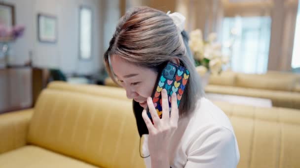 会話に従事する若いアジア人は 耳に電話をかけます 彼らはコミュニケーションの現代の世界で他の人とつながるように 彼らの顔に興味と感情の表現 — ストック動画