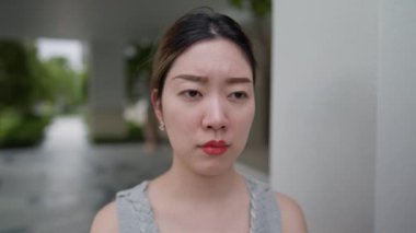 Yakın plan, Asyalı genç bir kadının yüzü stresin ağırlığını gösterir. İfadesi, hayatın zorluklarını yansıtan çeşitli duygular taşıyor. Savunmasızlığın ve esnekliğin güçlü bir tasviri.