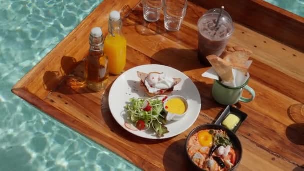 漂浮的早餐 沐浴在太阳的怀抱中 五彩缤纷的美味佳肴点缀着水面 为这一天创造了一个宁静而奢华的开始 高质量的4K镜头 — 图库视频影像
