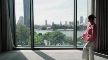 İlahi bir kadın büyük bir pencereye doğru yürür, gözleri görüş ve tefekkür ile doludur. Geniş bakış açısına hayran kalan kadın, bir anlık iç gözlem ve merakı somutlaştırıyor. Yüksek kalite 4k görüntü