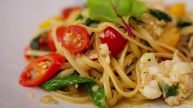 spagetti deniz ürünleri ağız sulandıran bir İtalyan lezzeti, lezzetli deniz ürünleriyle süslenmiş al dente makarna sergileniyor. Midye, karides ve istiridye aromalı domates sosu. Yüksek kalite 4k görüntü