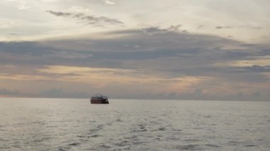 Vanilya gökyüzü, uzaktaki küçük bir tekneyle sakin bir sahne için zemin görevi görüyor. Sıcak, pastel renkler sakin suları sarıp rüya gibi bir görünüm yaratıyor. Yüksek kalite 4k görüntü