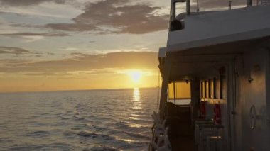 Gün batımı görüntüsü bir tekneden alındı. Güneşin altın rengi dalgalı suların üzerine sıcak bir parıltı saçarak nefes kesici bir deniz manzarası yaratır. Güzelliği özetleyen sakin bir an. Yüksek kalite 4k görüntü