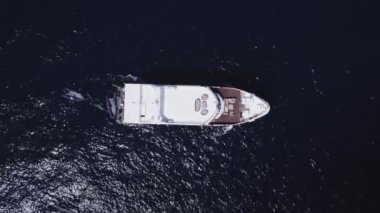 Göz kamaştırıcı yukarıdan görüntülü insansız hava aracı, güneşli bir günde okyanusun uçsuz bucaksız genişliğinde seyreden bir tekneyi yakalar. Taşıyıcı, sonsuz suyla çevrili, anlık bir yalnızlık anı yaratır..