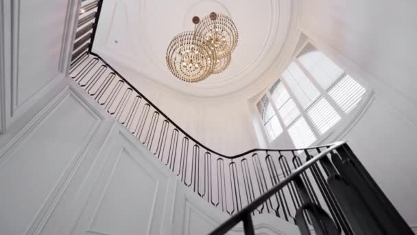 豪華なシャンデリアは円形の階段の上に飾られています 光と影は魅惑的な雰囲気を作り出し 建築の美しさと優雅さを強調しています 高品質の4K映像 — ストック動画