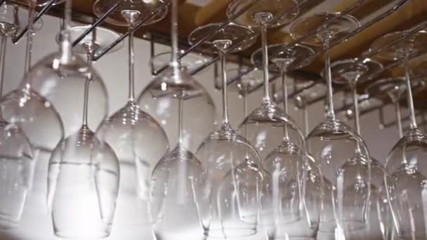 酒杯挂在吧台上方 形成迷人的陈列 水晶清澈的枝干和玻璃杯以完美的线条摇曳着 随时可以被填满和享用 为酒吧的氛围增添了美丽 — 图库视频影像