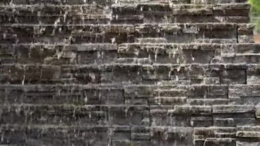İnsan yapımı bir şelalenin huzur dolu güzelliğini deneyimleyin, doğal ve büyüleyici bir odak noktası yaratan dokulu kayaları. Işık ve suyun etkileşimi derinlik katıyor. Yüksek kalite 4k görüntü