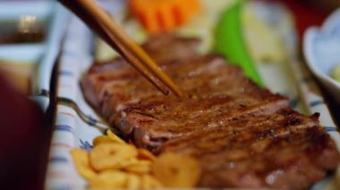 Kızarmış sarımsaklı ızgara Japon bifteği, yumuşak, sulu dokular ve zengin tatlar sergileniyor. Gurme mutfağı ve ağız sulandırıcı sunumları vurgulamak için mükemmel..