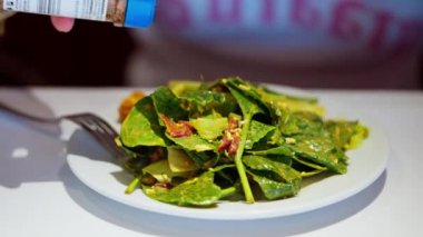 Büyük beyaz bir tabakta salatanın üzerine serpiştirilmiş taze, renkli malzemelerin altını çizmek için yakın plan. Zengin, aromalı soslar canlı sebzeleri geliştirir. Yüksek kalite 4k görüntü
