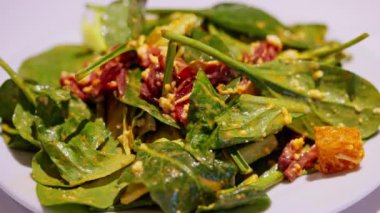 Büyük beyaz bir tabakta sunulan taze salatanın yakın çekimi, renkli sebzeler, yapraklı yeşiller ve canlı malzemeler içeriyor. Temiz, zarif sunum tazeliği ve görsel cazibe.