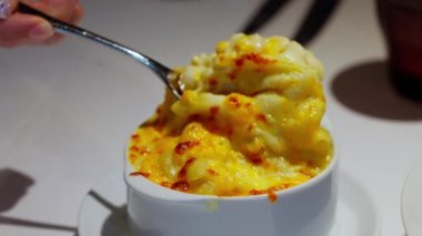 Bir kaşığın yakın çekimi kremalı makarna ve peynir topluyor, tabaktan erimiş peynir sergileniyor. Zengin, altın makarna ve peynirli sos rahatlatıcının altını çiziyor. Yüksek kalite 4k görüntü