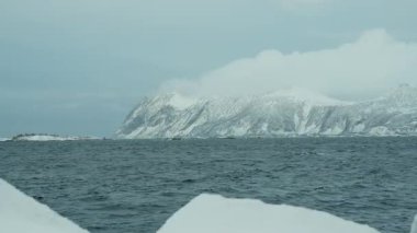 Sinema videosunda karla kaplı dağların okyanusla buluşmasına tanık olun. Buzlu zirveler derin mavi suların üzerinde dramatik bir şekilde yükseliyor, nefes kesici bir kış manzarası..