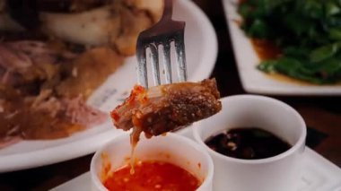 Kızarmış domuz bacağının tuzlu sosa batırıldığı yakın plan. Altın, çıtır çıtır dokular, aşçılık videoları ve yemek tanıtımları için mükemmel olan zengin ve lezzetli sosla çelişiyor..