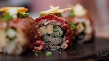 Bir Japon restoranında sunulan lüks Wagyu bifteklerinin yakın çekimi, özenle sarılmış ve zarifçe süslenmiş mermer et sergileniyor. Gurme yemekler için zengin doku ve ince sunum.