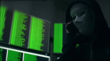 Beyaz Maskeli Sanal Korsan Bilgisayar Sistemi 'ni hacklerken telefonda konuşuyor. ARRI Alexa ile ARRIRAW 'da çekildi ve QuickTime Apple ProRes 422 HQ ihraç edildi..