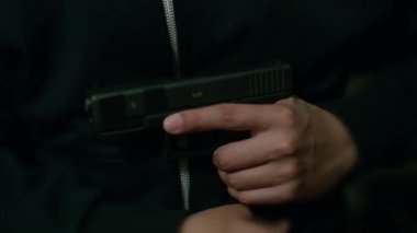 Latin erkek suçlu, silahı cebinden çıkarıp etrafa bakınıyor. ARRI Alexa ile ARRIRAW 'da çekildi ve QuickTime Apple ProRes 422 HQ ihraç edildi..