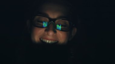 Güzel beyaz kadın cep telefonu kullanıyor, gülüyor, karanlık arka plan. ARRI Alexa ile 120 fps hızla ArriRaw 'da çekilmiş, 23.98 fps QuickTime Apple ProRes 422 HQ ihraç edilmiş..