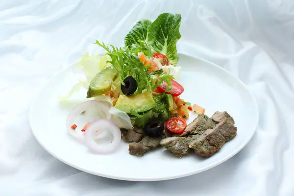 Dilimlenmiş avokado, domates ve taze sebzeli kurutulmuş sığır eti salatası. İnce dilimlenmiş saşimi tarzı..