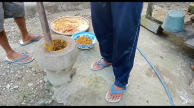 Köylüler doğal taştan yapılmış geleneksel Endonezya ezme araçları ve Lumpang adında bir odun parçası kullanarak mutfak baharatlarını dövüyorlar..