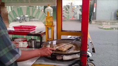 Tabanan, Bali, Endonezya - 13 Eylül 2024: Sokak gıda satıcıları Kediri, Tabanan, Bali 'de öğleden sonra lezzetli bir tat alabilmek için düşük sıcakta yumurta martabak kızartıyorlar.