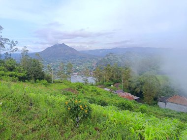 Sabahleyin Kintamani Bali 'nin yeşil tepelerinden görülen Batur Dağı manzarası.