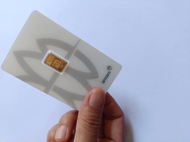 Bali, Endonezya - 13 Nisan 2025: Beyaz zemin üzerinde bir el 2 gram Antam altını tutuyor. Antam Gold, Endonezya 'da PT Aneka Tambang Tbk tarafından üretilen bir altın külçesidir..