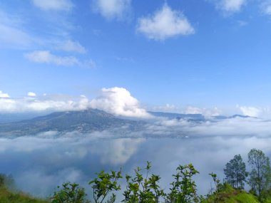 Batur Dağı, Bangli, Bali dağları kaplayan beyaz bulutlarla süslenmiş parlak mavi gökyüzü.