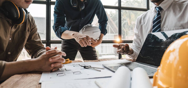 Civil engineer teams meeting working together wear worker helmets hardhat on construction site in modern city. Foreman industry project manager engineer teamwork. Asian industry professional team