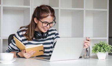 Asyalı kız öğrenci çevrimiçi sınıfta çalışıyor, çevrimiçi çalışıyor, kulaklık takıyor, video izliyor, zumluyor, bilgisayarlı dizüstü bilgisayarla mutlu Asyalı kadın öğrenme dili öğreniyor...