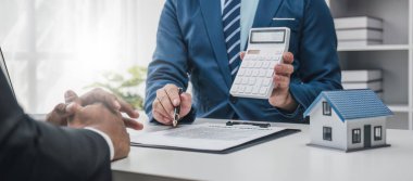 Emlakçı ve müşteriyle ev modeli satın alma, sigorta ya da kredi alma ya da emlak ya da mülkiyet sözleşmesi hakkında tartışıyor