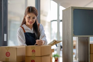 Küçük işletme girişimcisi KME, kutuda kumaş paketleyen Asyalı kadın. Portre genç Asyalı küçük işletme sahibi ev sahibi, çevrimiçi satış pazarlama teslimatı, KME e-ticaret tele pazarlama kavramı.