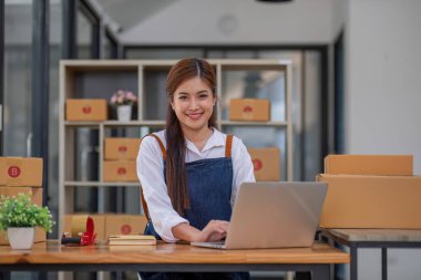 Küçük işletme girişimcisi KME, kutuda kumaş paketleyen Asyalı kadın. Portre genç Asyalı küçük işletme sahibi ev sahibi, çevrimiçi satış pazarlama teslimatı, KME e-ticaret tele pazarlama kavramı.