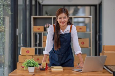 Küçük işletme girişimcisi KME, kutuda kumaş paketleyen Asyalı kadın. Portre genç Asyalı küçük işletme sahibi ev sahibi, çevrimiçi satış pazarlama teslimatı, KME e-ticaret tele pazarlama kavramı.