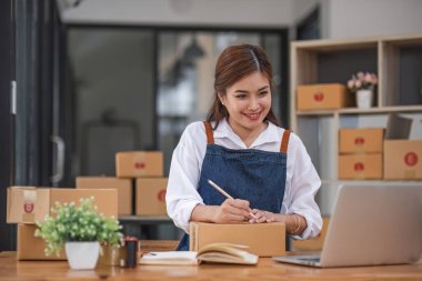 Startup small business entrepreneur SME, asian woman packing cloth in box. Portrait young Asian small business owner home office, online sell marketing delivery, SME e-commerce telemarketing concept.