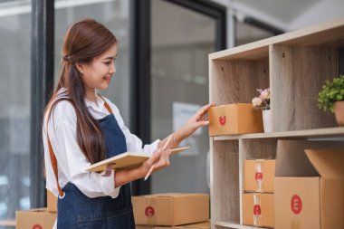Startup small business entrepreneur SME, asian woman packing cloth in box. Portrait young Asian small business owner home office, online sell marketing delivery, SME e-commerce telemarketing concept.
