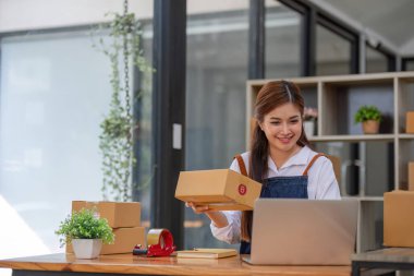 Küçük işletme girişimcisi KME, kutuda kumaş paketleyen Asyalı kadın. Portre genç Asyalı küçük işletme sahibi ev sahibi, çevrimiçi satış pazarlama teslimatı, KME e-ticaret tele pazarlama kavramı.