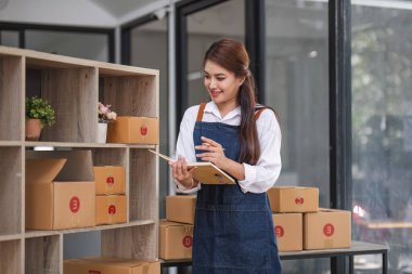 Küçük işletme girişimcisi KME, kutuda kumaş paketleyen Asyalı kadın. Portre genç Asyalı küçük işletme sahibi ev sahibi, çevrimiçi satış pazarlama teslimatı, KME e-ticaret tele pazarlama kavramı.