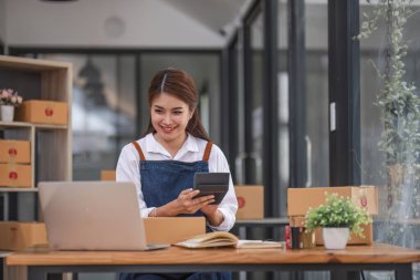 Küçük işletme girişimcisi KME, kutuda kumaş paketleyen Asyalı kadın. Portre genç Asyalı küçük işletme sahibi ev sahibi, çevrimiçi satış pazarlama teslimatı, KME e-ticaret tele pazarlama kavramı.