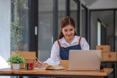 Küçük işletme girişimcisi KME, kutuda kumaş paketleyen Asyalı kadın. Portre genç Asyalı küçük işletme sahibi ev sahibi, çevrimiçi satış pazarlama teslimatı, KME e-ticaret tele pazarlama kavramı.