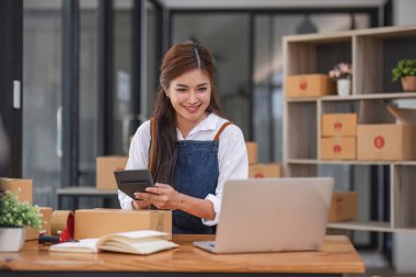 Startup small business entrepreneur SME, asian woman packing cloth in box. Portrait young Asian small business owner home office, online sell marketing delivery, SME e-commerce telemarketing concept.